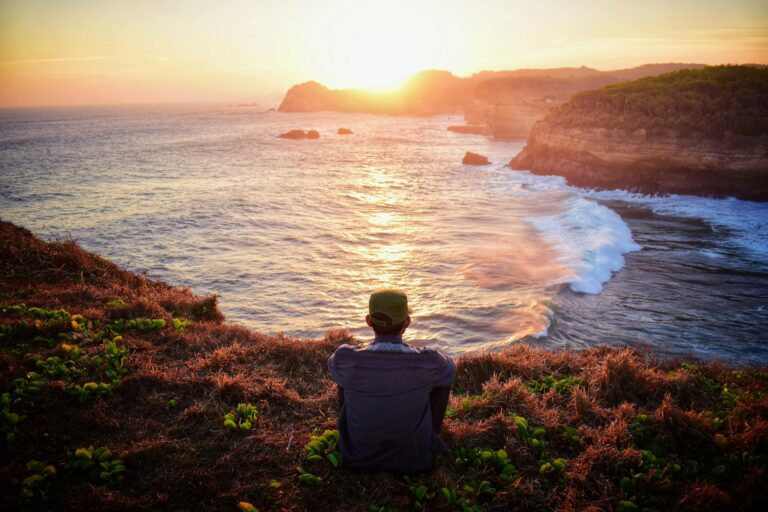 man staring at sunset in nature